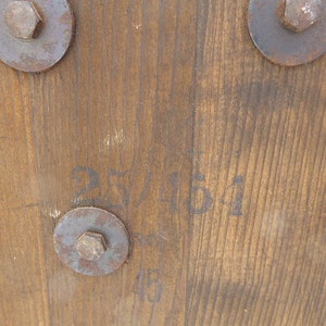 May include: Close-up of a wooden surface with three metal fasteners and the text "25/11/51" written in black ink.