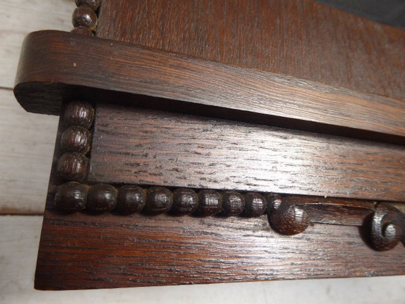 May include: Close-up of a dark brown wooden frame with a beaded trim. The frame has a smooth, polished finish and a slightly raised edge.