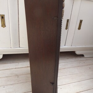 May include: A dark brown wooden wall mounted cabinet with intricate carvings and a beaded trim. The cabinet has a single door and is closed.