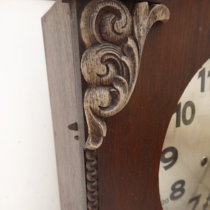 May include: A vintage wooden clock with a white face and black numbers. The clock has a decorative carved wooden frame with a gold-painted finish.