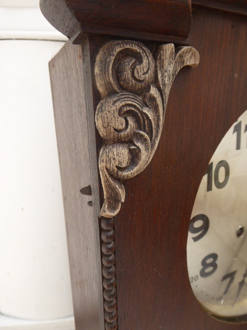 May include: A vintage wooden clock with a white face and black numbers. The clock has a decorative carved wooden frame with a gold-painted finish.