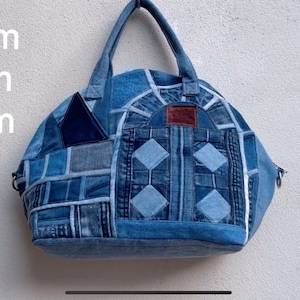Könnte beinhalten: Eine blaue Denim-Tragetasche mit Patchwork-Details. Die Tasche hat einen oberen Griff und einen Reißverschluss. Die Tasche misst 30 cm in der Breite, 16 cm in der Tiefe und 30 cm in der Höhe.