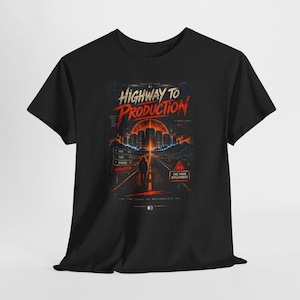 May include: A black t-shirt featuring a graphic print of a road leading toward a glowing orange city skyline under a large sun. The text reads HIGHWAY TO PRODUCTION, DEV, TEST, STAGING, PRODUCTION, and ONE MORE DEPLOYMENT with a warning sign icon.