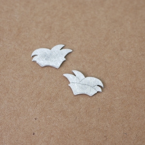 Könnte beinhalten: Zwei silberfarbene Metall-Narrenkappen auf braunem Hintergrund.