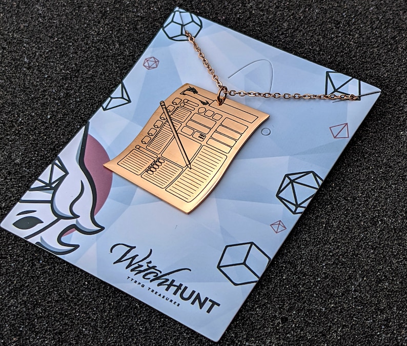 Rose gold character sheet necklace pendant displayed on branded card. Perfect D&D character sheet jewelry for tabletop RPG fans seeking unique Dungeons & Dragons accessories.