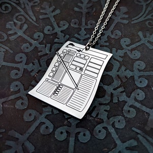 Silver character sheet pendant necklace on a dark fantasy-themed background. Ideal TTRPG character sheet jewelry for D&D players who love fantasy-inspired accessories.