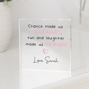 May include: A clear acrylic block with the text "Chance made us COLLEAGUES, fun and laughter made us FRIENDS" and a pink heart. The text "Love Sarah" is written below the text.
