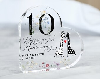 May include: A clear heart-shaped acrylic keepsake with a floral design and the number 10. The text "Happy Tin Anniversary" is written in cursive. Two giraffes are kissing with a red heart between them. The text "MARIA & STEVE 27.08.2014" is written below the giraffes.