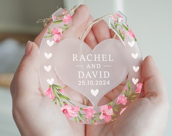 May include: A white horseshoe-shaped ornament with pink floral accents and a heart-shaped cutout. The heart has the text "Rachel and David 25.10.2024" printed on it.