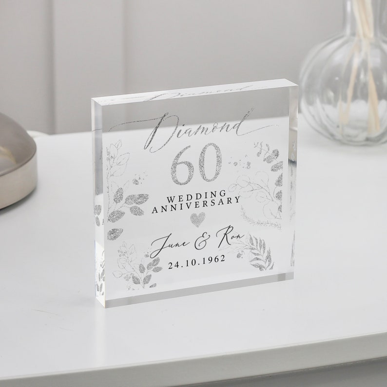 K&ouml;nnte beinhalten: Ein klarer Acrylblock mit einem silbernen Glitzerdesign. Der Block zeigt den Text "Diamond 60 Wedding Anniversary June & Ron 24.10.1962".