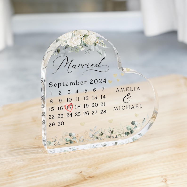May include: A clear heart-shaped acrylic keepsake with a floral design and the words "Married" and "September 2024". The calendar shows the date "17" highlighted with a red heart. The names "Amelia & Michael" are also included.