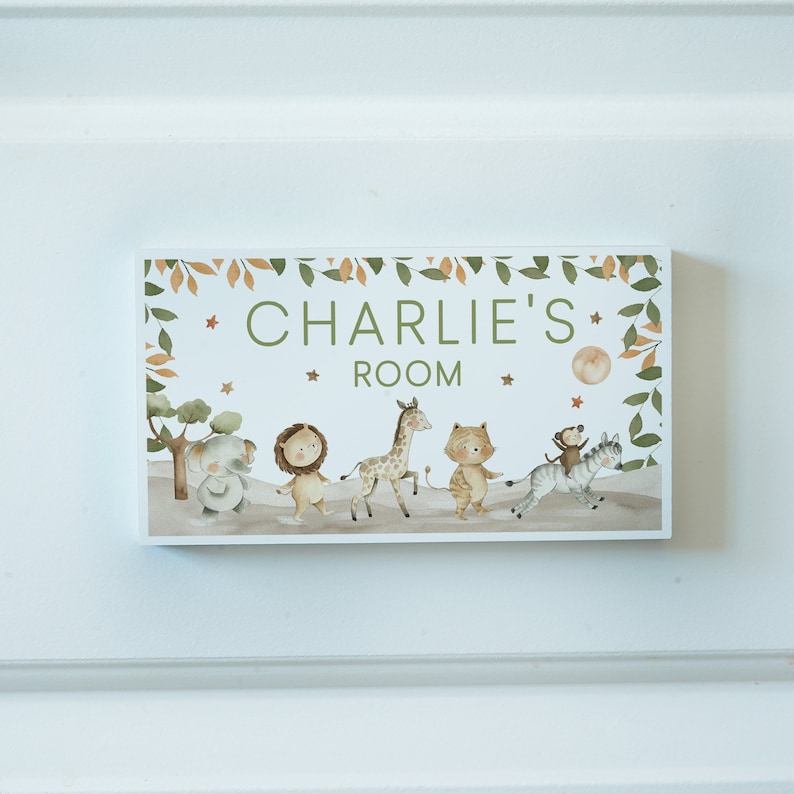 May include: A wooden sign with a green leafy border and a white background. The sign says "Charlie's Room" in green letters. There are illustrations of animals including a lion, giraffe, elephant, monkey, and zebra.