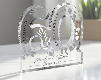 May include: A clear acrylic 60th anniversary keepsake with a floral design. The text "Diamond Anniversary" is on the left side of the number 60. The text "Marilyn & Steve 28.09.1965" is on the base.