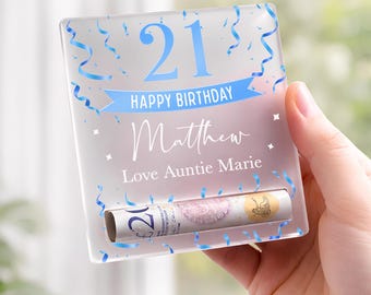May include: A clear acrylic birthday card holder with blue accents, confetti, and ribbons. The card reads "21 Happy Birthday Matthew Love Auntie Marie." A rolled-up bill is visible in the slot.