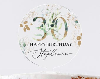 May include: A round, clear acrylic cake topper with a gold and green floral design. The number 30 is in the center, with the text "Happy Birthday Stephanie" below.
