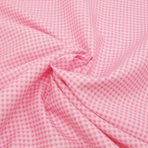 May include: Pink and white gingham fabric with a checkered pattern. The fabric is folded and wrinkled.