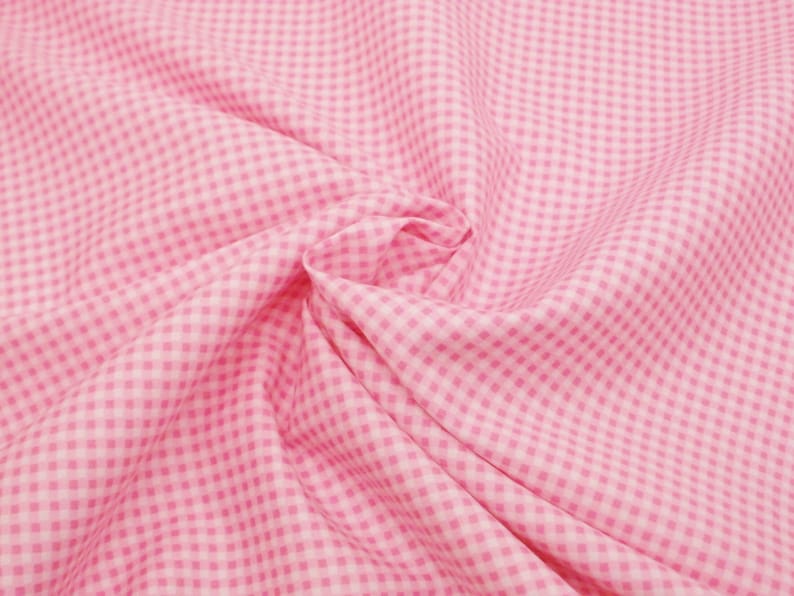 May include: Pink and white gingham fabric with a checkered pattern. The fabric is folded and wrinkled.
