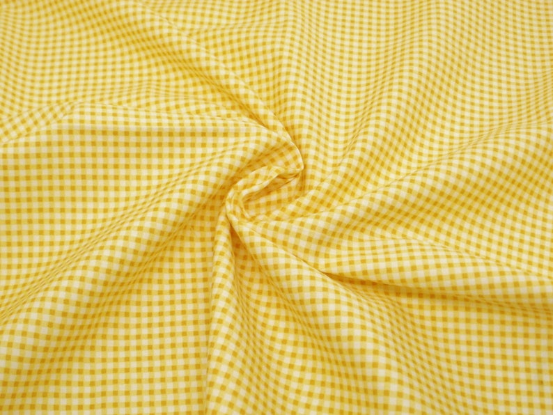 May include: Yellow and white gingham fabric with a small checkered pattern. The fabric is folded and wrinkled.