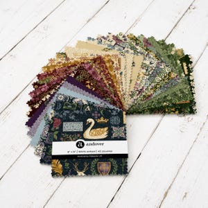 May include: A stack of 42 square fabric pieces with pinked edges, featuring various patterns in shades of green, gold, cream, and dark blue. The label reads: andover, 5" x 5" | 100% cotton | 42 squares, Kindred by Makower UK. Designs include swans, crowns, and foliage.
