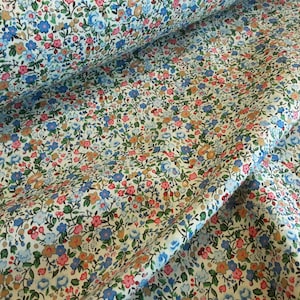 May include: White fabric with a small floral print in shades of blue, pink, and brown. The fabric is folded in half, showing the pattern on both sides.