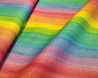 May include: A close-up of a fabric with a watercolor rainbow pattern. The fabric is folded, showing layers of color. The colors include red, orange, yellow, green, blue, and purple, creating a vibrant and cheerful design.