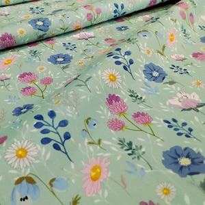 May include: A floral fabric with a pale green backdrop, adorned with a variety of flowers. The pattern includes blooms in pink, blue, and white, complemented by green foliage and stems. The material is likely cotton or a similar textile.