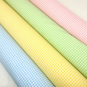 May include: Four rolls of gingham fabric in blue, yellow, green, and pink.