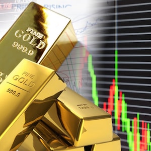 Può includere: Lingotti d'oro impilati uno sopra l'altro con le parole "FINE GOLD 999.9" stampate sui lingotti. I lingotti sono davanti a un grafico azionario con linee rosse e verdi.