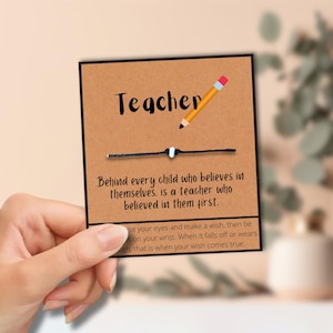 Puede incluir: Una tarjeta marrón con la palabra "Teacher" en escritura negra, una ilustración de lápiz y una pulsera de cuerda negra. La tarjeta dice: "Detrás de cada niño que cree en sí mismo, hay un maestro que creyó en ellos primero."