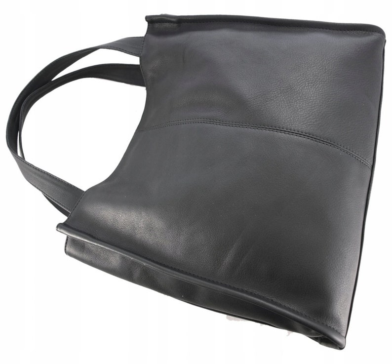 May include: Black leather tote bag with a rectangular shape and a single shoulder strap. The bag features a stitched horizontal seam across the middle and a smooth, matte finish. The strap is thin and made of the same material as the bag.