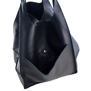 May include: A dark blue leather tote bag with a large pocket on the front. The bag has a single snap closure.