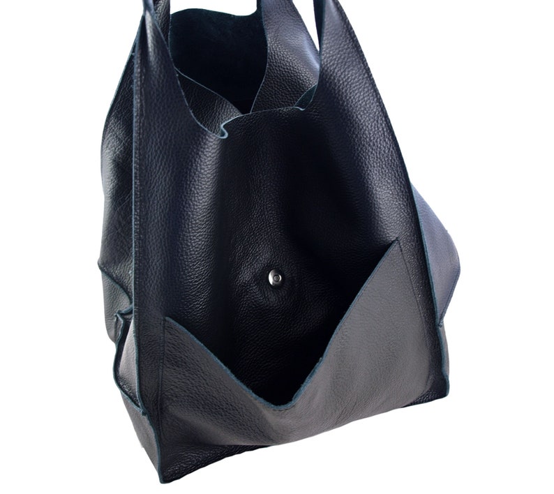 May include: A dark blue leather tote bag with a large pocket on the front. The bag has a single snap closure.
