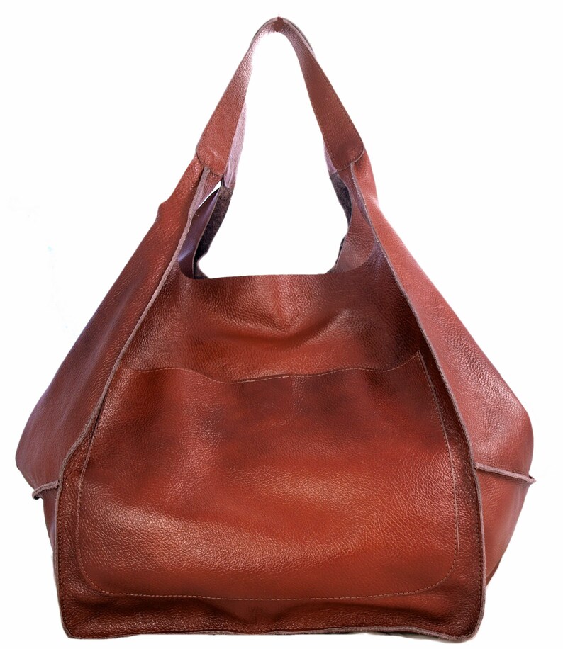 Puede incluir: Un bolso tote de cuero marr&oacute;n con un solo asa superior. El bolso tiene una parte superior grande y abierta y un solo bolsillo en la parte delantera.
