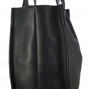 May include: A black tote bag with two long handles. The bag is made of a textured material and has a rectangular shape. The handles are attached to the top of the bag.