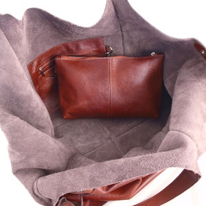 Puede incluir: Un bolso tote de cuero marr&oacute;n con un bolsillo con cremallera y una bolsa de cuero marr&oacute;n m&aacute;s peque&ntilde;a en el interior. El bolso est&aacute; abierto y el forro es de ante marr&oacute;n claro.