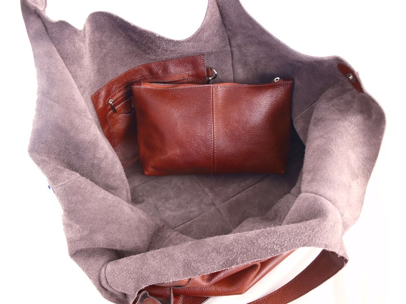Puede incluir: Un bolso tote de cuero marr&oacute;n con un bolsillo con cremallera y una bolsa de cuero marr&oacute;n m&aacute;s peque&ntilde;a en el interior. El bolso est&aacute; abierto y el forro es de ante marr&oacute;n claro.