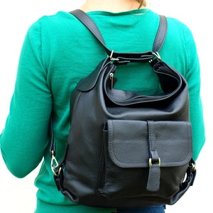 May include: Black leather backpack with a flap pocket and adjustable straps. The backpack has a zippered main compartment and a top handle. The leather has a textured appearance. The hardware is silver-colored.