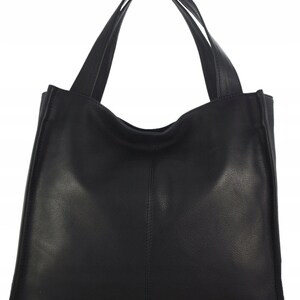 May include: A black tote bag with two long handles. The bag is made of a smooth, matte material and has a rectangular shape with a slightly curved top. The handles are attached to the top of the bag and are wide enough to be carried over the shoulder.