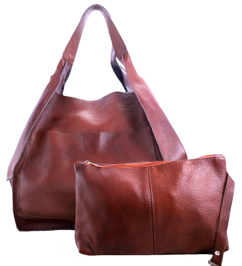 Puede incluir: Un bolso tote de cuero marr&oacute;n con una bolsa de cuero marr&oacute;n a juego. El bolso tote tiene una parte superior grande y abierta y dos asas largas. La bolsa tiene una cremallera y una correa peque&ntilde;a.