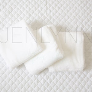 May include: Three white, fluffy pillows arranged on a white quilted surface. The pillows are soft and plush, perfect for a comfortable and cozy setting.