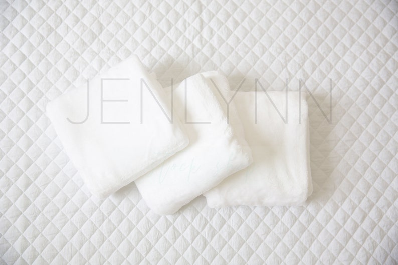 May include: Three white, fluffy pillows arranged on a white quilted surface. The pillows are soft and plush, perfect for a comfortable and cozy setting.