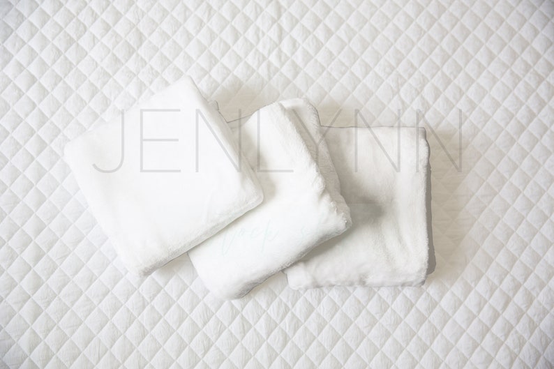 May include: Three white, fluffy, rectangular pillows arranged on a white quilted surface. The pillows are soft and plush, perfect for a cozy and comfortable setting.