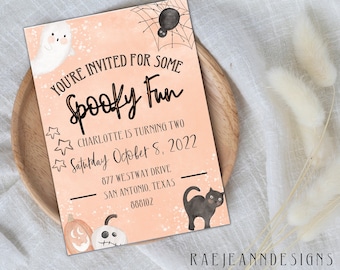 May include: A peach-colored invitation card with black text and illustrations. The text reads "You're invited for some Spooky Fun - Charlotte is turning two - Saturday October 8, 2022 - 877 Westway Drive, San Antonio, Texas 880102". The illustrations include a ghost, a spider, a black cat, and pumpkins.