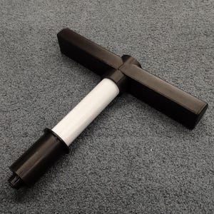 Puede incluir: Una herramienta de plástico negro en forma de T con una sección central blanca. La herramienta tiene una pequeña abertura en forma de estrella en un extremo.