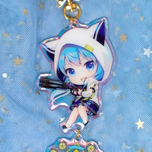 May include: A blue and white anime character keychain with a gun and a yellow and blue axe charm. The character has blue hair and is wearing a white hooded jacket with cat ears.