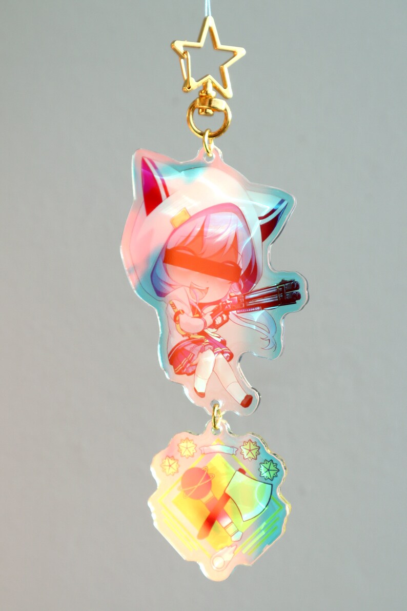 May include: A colorful anime character keychain with a white hooded jacket, blue hair, and a gun. The keychain also features a separate charm with a yellow background and a red axe and a baseball bat.