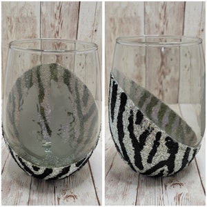 Puede incluir: Dos copas de vino de vidrio transparente con un diseño de cebra en blanco y negro en la mitad inferior del vaso.