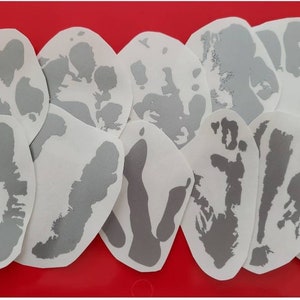 May include: A set of 12 silver-colored vinyl stickers featuring a unique design of a handprint. The stickers are on a white background.