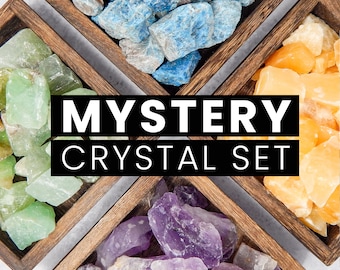 Op de afbeelding: Vier houten dozen gevuld met verschillende soorten kristallen. De dozen zijn in een kruispatroon gerangschikt. De tekst "MYSTERY CRYSTAL SET" wordt in het midden van de afbeelding weergegeven.
