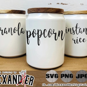 Puede incluir: Tres botes de cerámica blanca con tapas de madera. Los botes están etiquetados con "granola", "palomitas de maíz" y "arroz instantáneo".